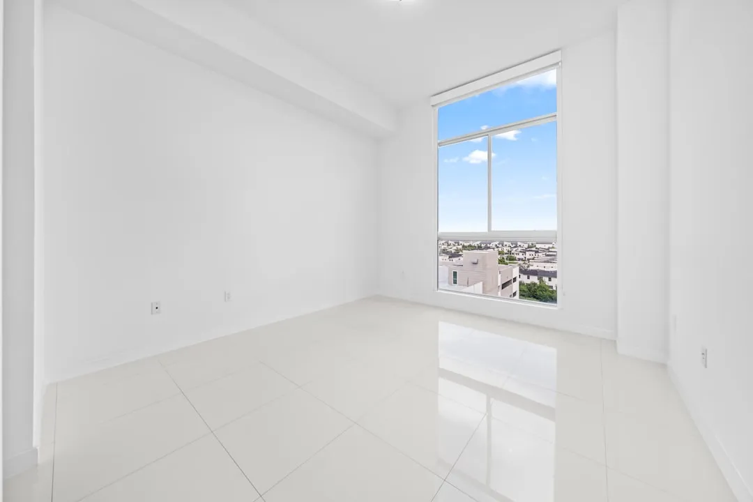 Empty white room with a large window overlooking city