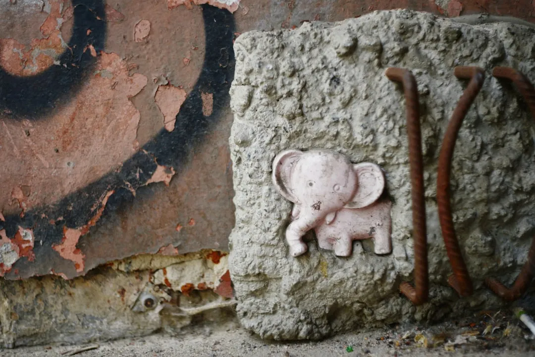 Pink elephant figurine on a textured concrete block.